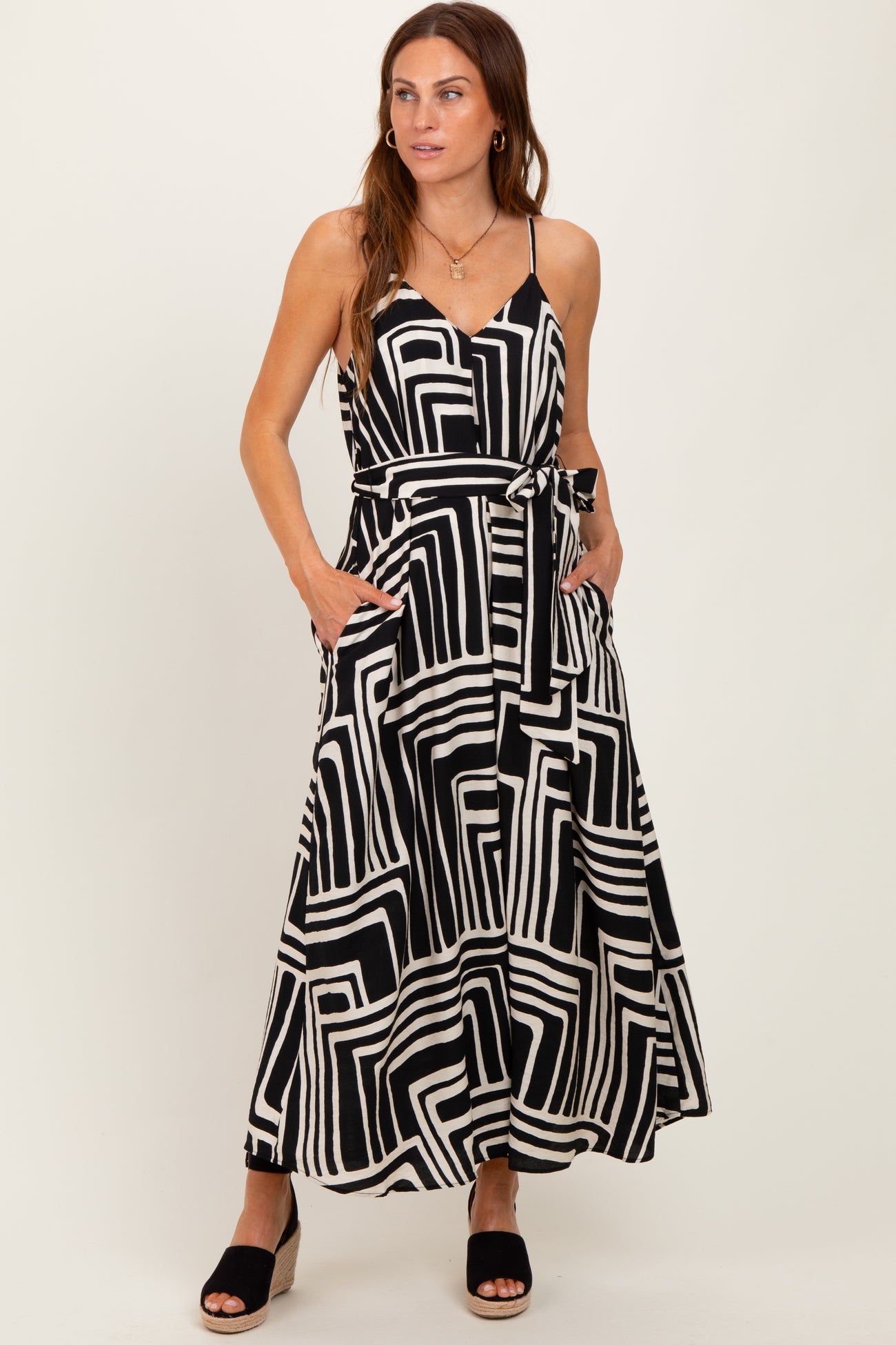 woman wearing a black and white geometric print maxi dress with pockets and a tie waist