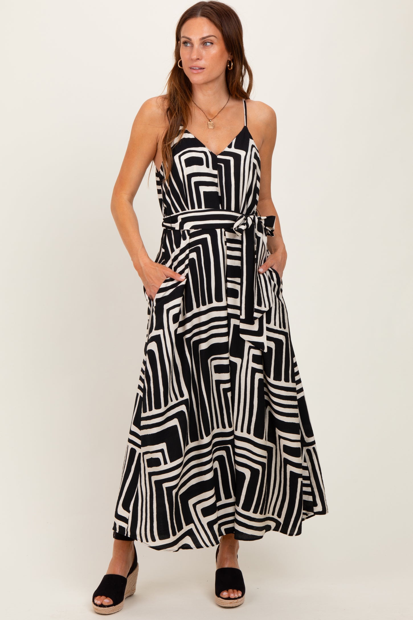 woman wearing a black and white geometric print maxi dress with pockets and a tie waist