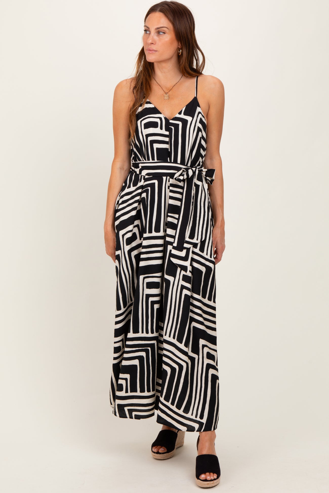 woman wearing a black and white patterned maxi dress with a tie waist and spaghetti straps