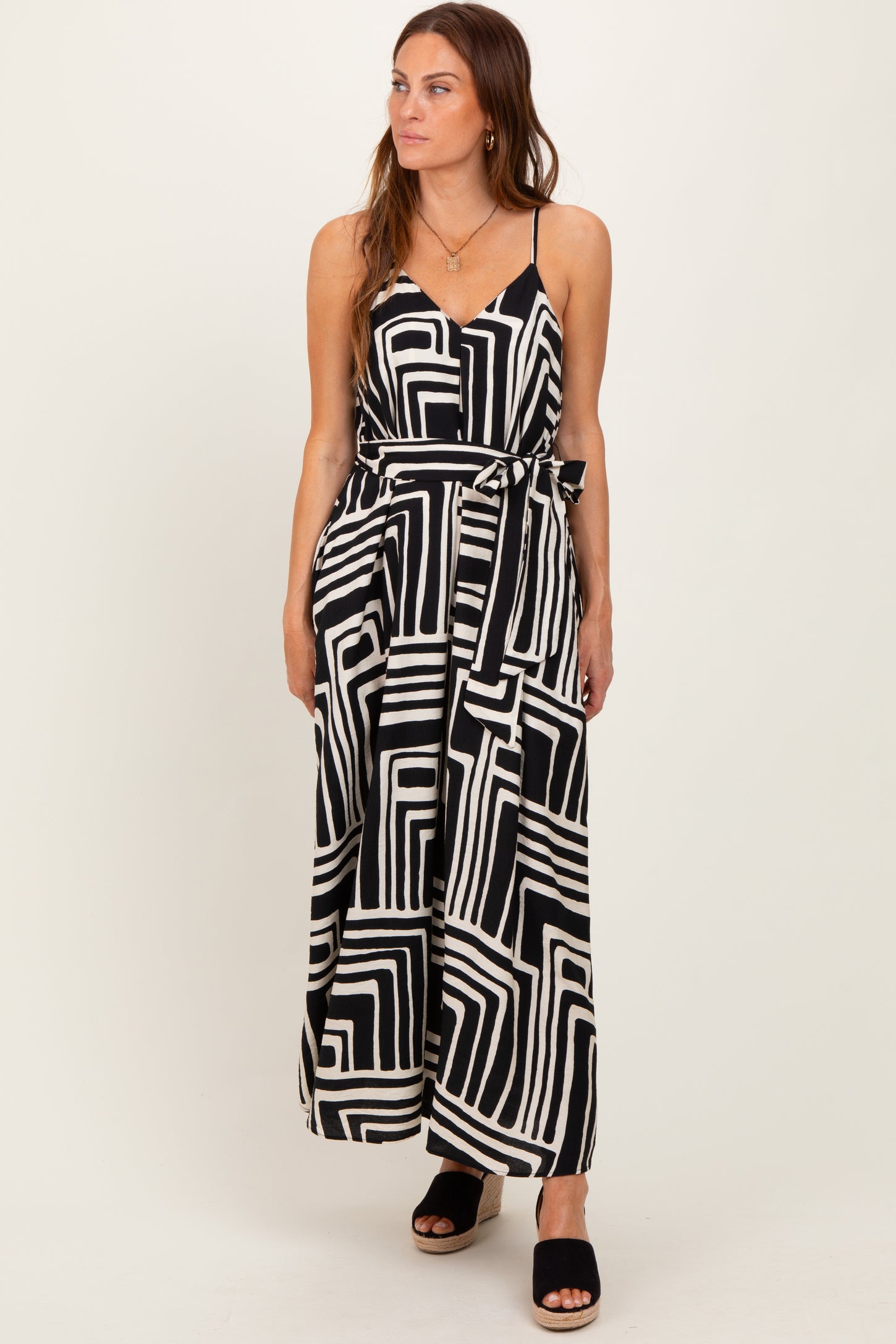 woman wearing a black and white patterned maxi dress with a tie waist and spaghetti straps