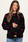 woman wearing a black maternity sweater with pink heart patterns and holding her baby bump