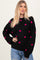 woman wearing a black sweater with pink heart patterns and relaxed fit, paired with light blue jeans