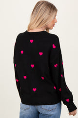 woman wearing a black sweater with pink heart patterns and a relaxed fit, viewed from the back