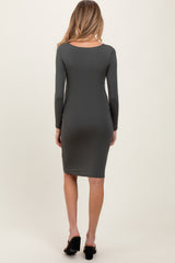 woman wearing a dark green long sleeve maternity dress, viewed from the back, fitted style