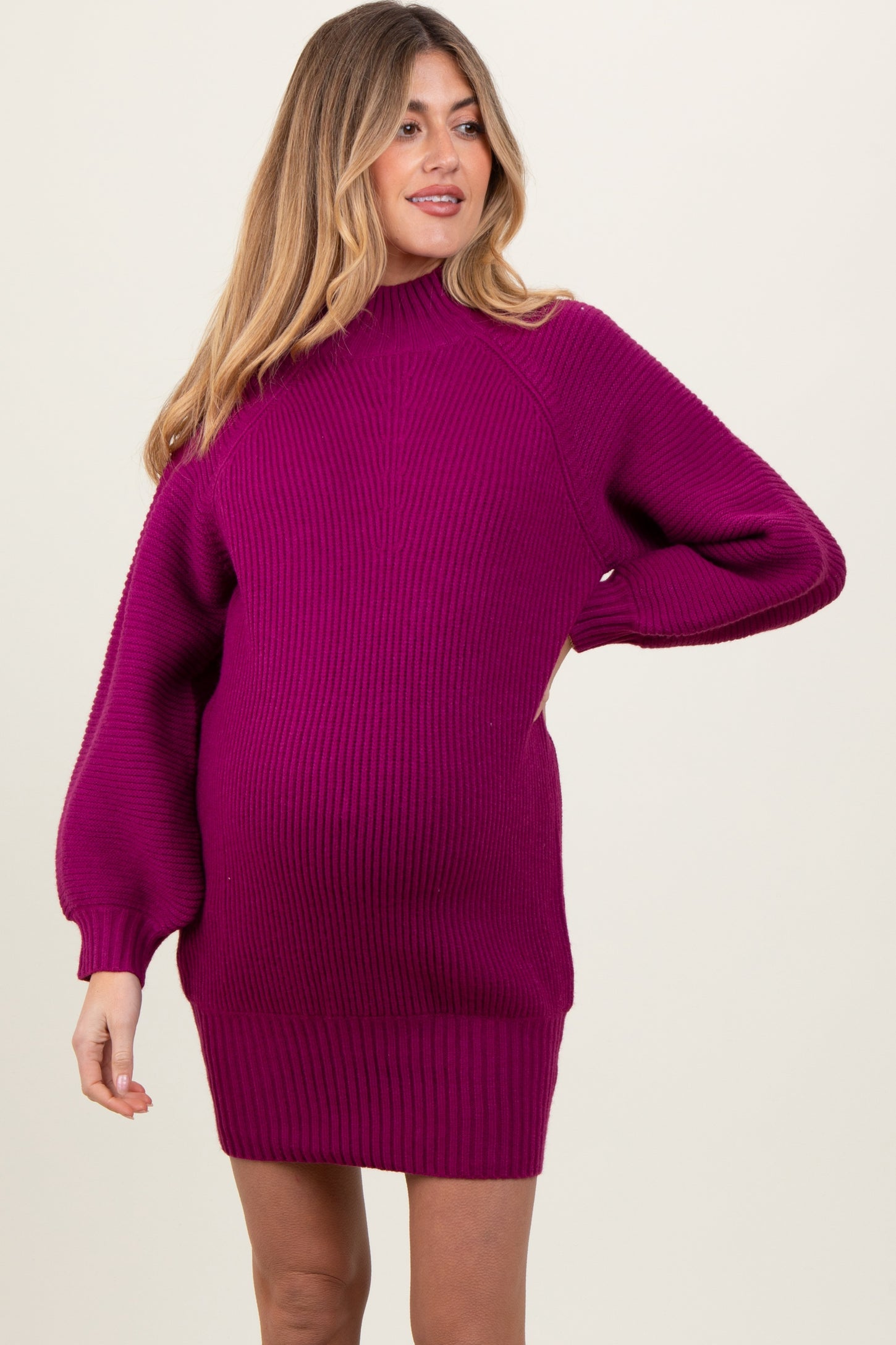 woman wearing a fuchsia ribbed maternity sweater dress with a fitted silhouette and baby bump visible