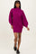 woman wearing a bold magenta oversized sweater dress with balloon sleeves and a high neckline