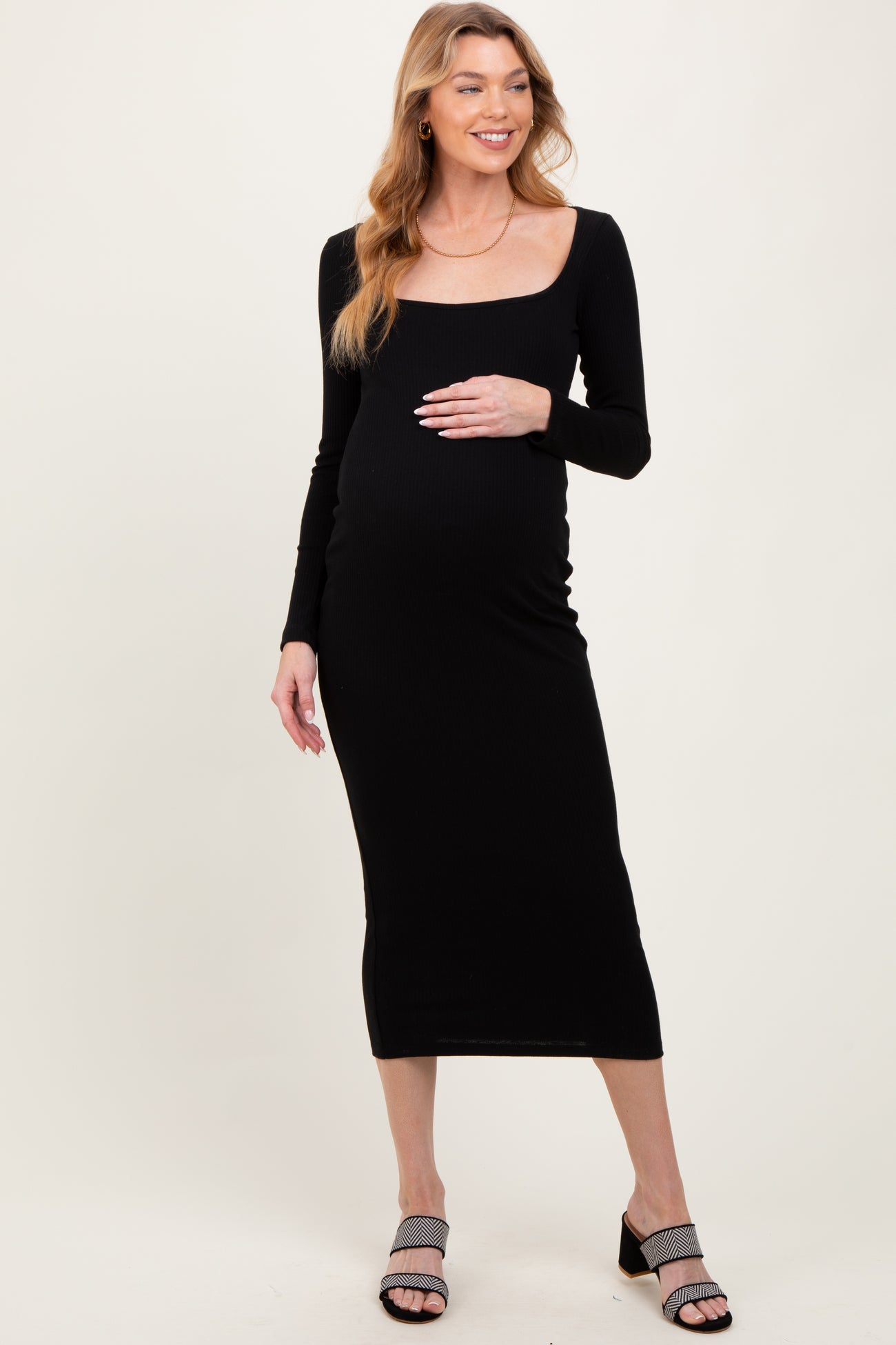 woman wearing a black long sleeve maternity dress and holding her baby bump