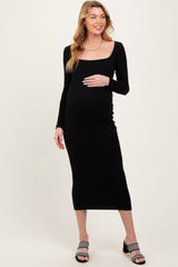 woman wearing a black long sleeve maternity dress and holding her baby bump