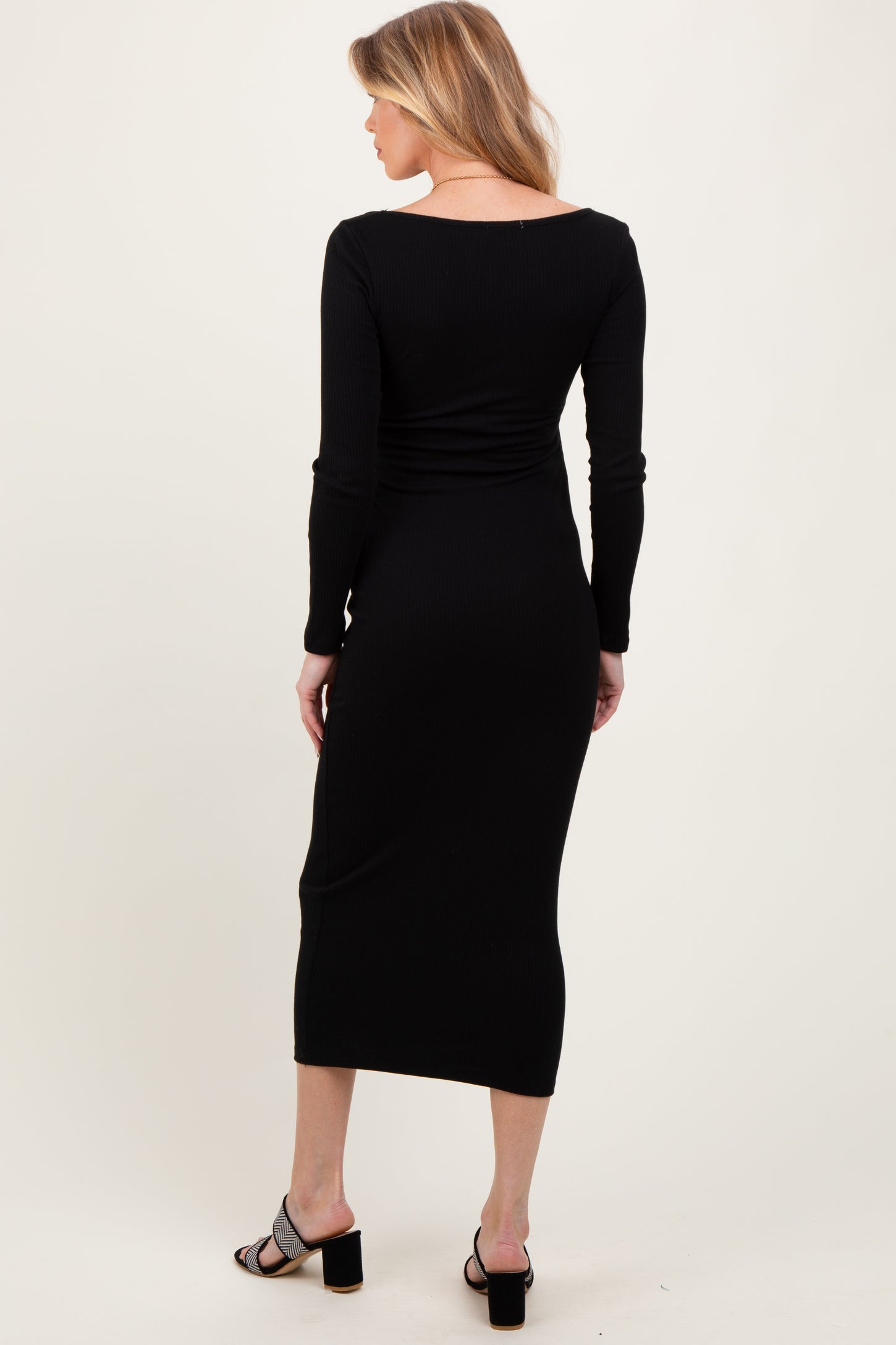 woman wearing a black long sleeve maternity dress with a form-fitting silhouette, showcasing a smooth back view