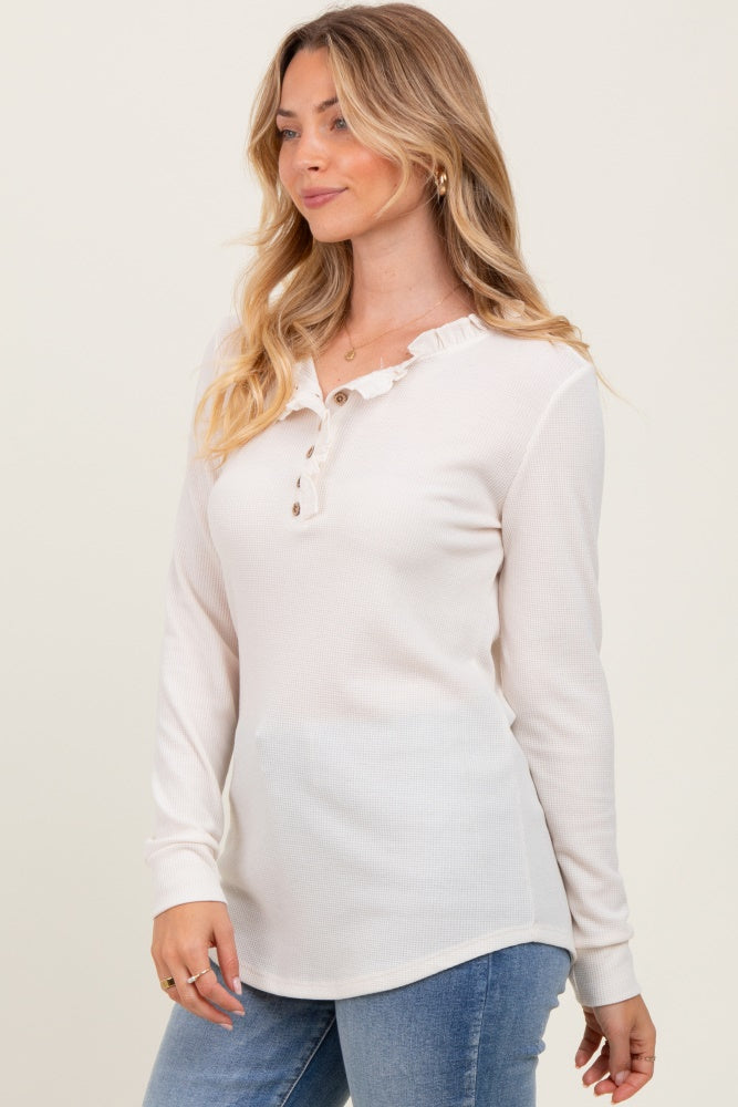 woman wearing a light pink long sleeve henley top with ruffle detail and button closure, paired with denim jeans