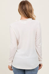 woman wearing a light beige long sleeve top with a ruffle neckline and a slim fit, seen from the back