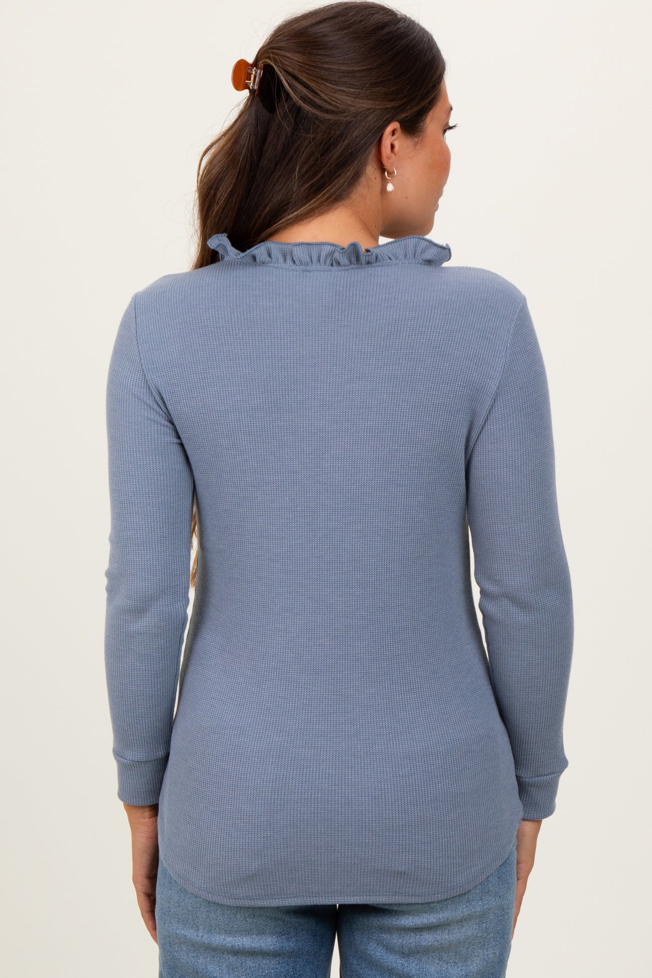 woman wearing a light blue long sleeve maternity top with a ruffled neckline, shown from the back