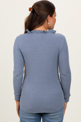 woman wearing a light blue long sleeve maternity top with a ruffled neckline, shown from the back