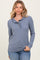 woman wearing a blue long sleeve henley top with ruffle detail and button closure, styled casually with jeans