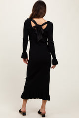 woman wearing a black ribbed midi dress with long sleeves and a bow detail at the back