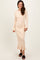 woman wearing a light beige ribbed long sleeve dress with bell sleeves and a ruffled hem, standing and smiling