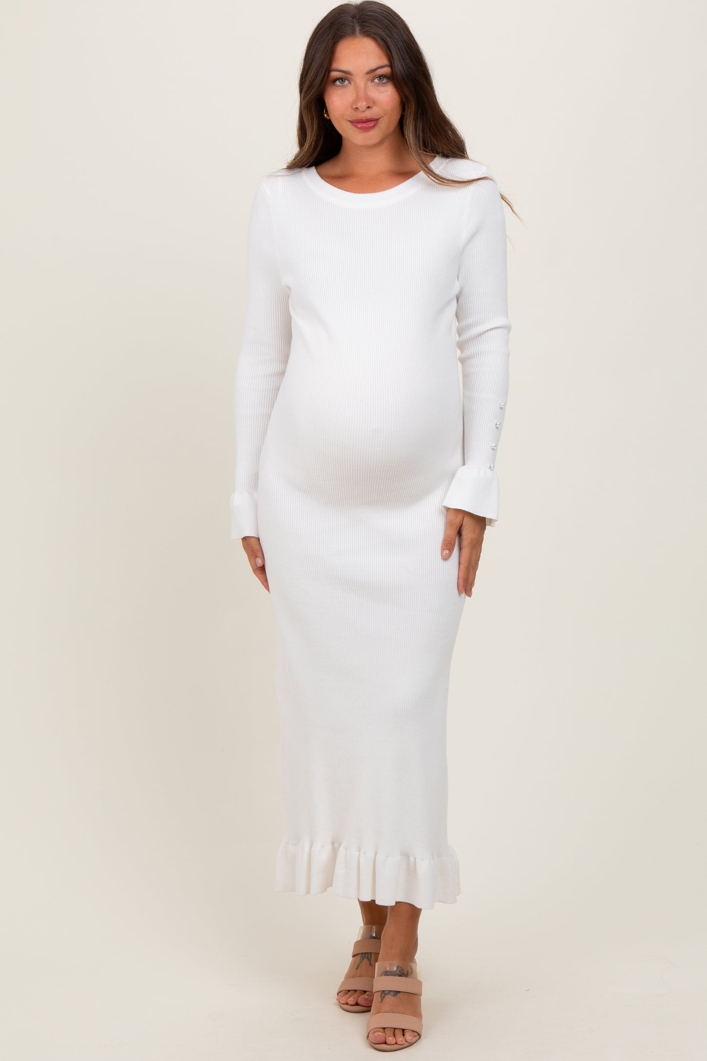 woman wearing a white ribbed maternity dress with long sleeves and frill hem, showing baby bump