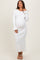 woman wearing a white ribbed maternity dress with fluted hem and long sleeves, showing her baby bump