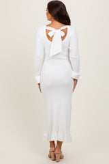 woman wearing a white ribbed maternity dress with a back bow tie and ruffled hem
