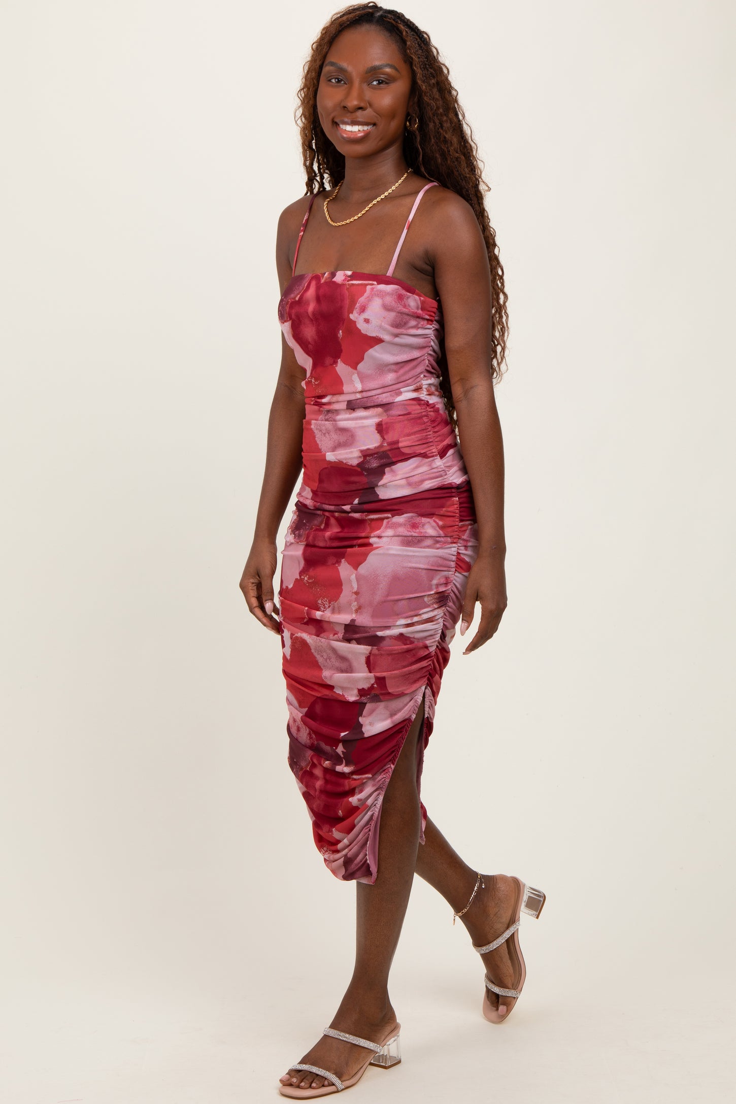 woman wearing a red and pink floral bodycon dress with ruching and side slit
