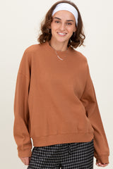 woman wearing an oversized brown sweatshirt with dropped shoulders and a relaxed fit