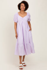 woman wearing a lavender striped midi dress with puff sleeves and a tiered hem, smiling at the camera
