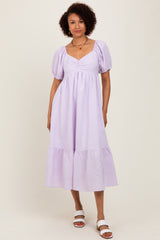 woman wearing a lavender striped puff sleeve midi dress with a tiered hem and a square neckline