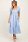 woman wearing a light blue striped midi dress with puff sleeves and pockets, smiling against a neutral background