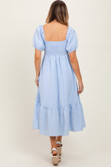 woman wearing a light blue striped midi dress with puff sleeves and a smocked bodice, shown from the back