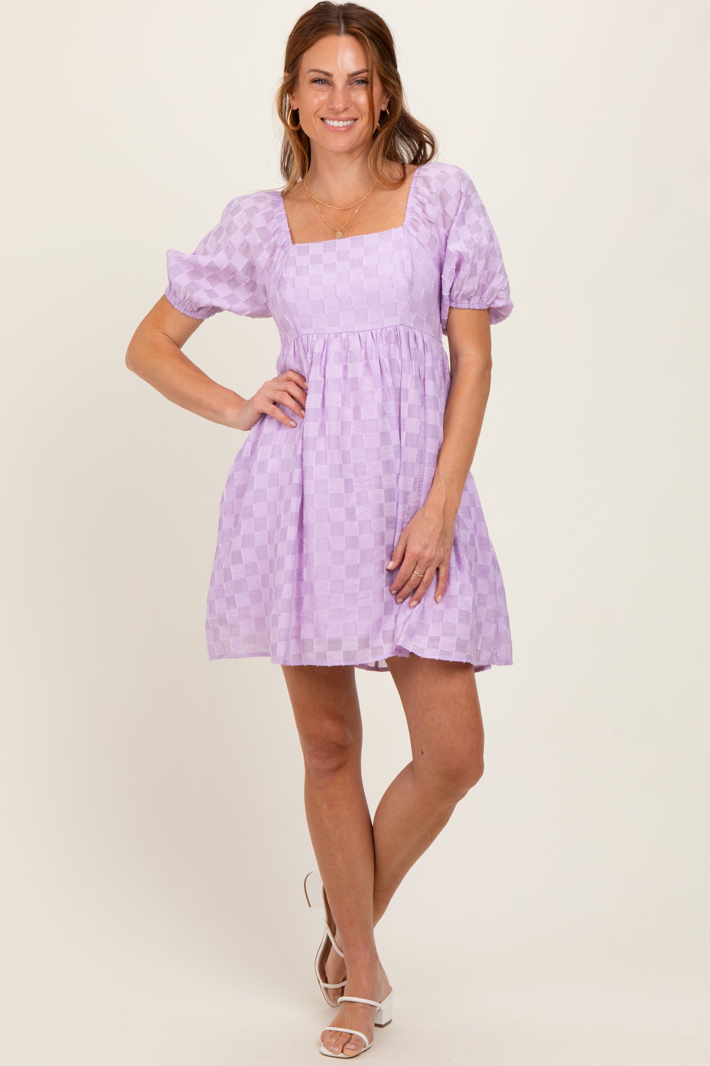 woman wearing a lavender checkered short puff sleeve dress with a square neckline and flared skirt