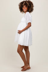 woman wearing a white short puff sleeve maternity dress and holding her baby bump