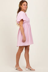 woman wearing a pink puff sleeve mini dress with a cinched waist and relaxed fit, standing sideways