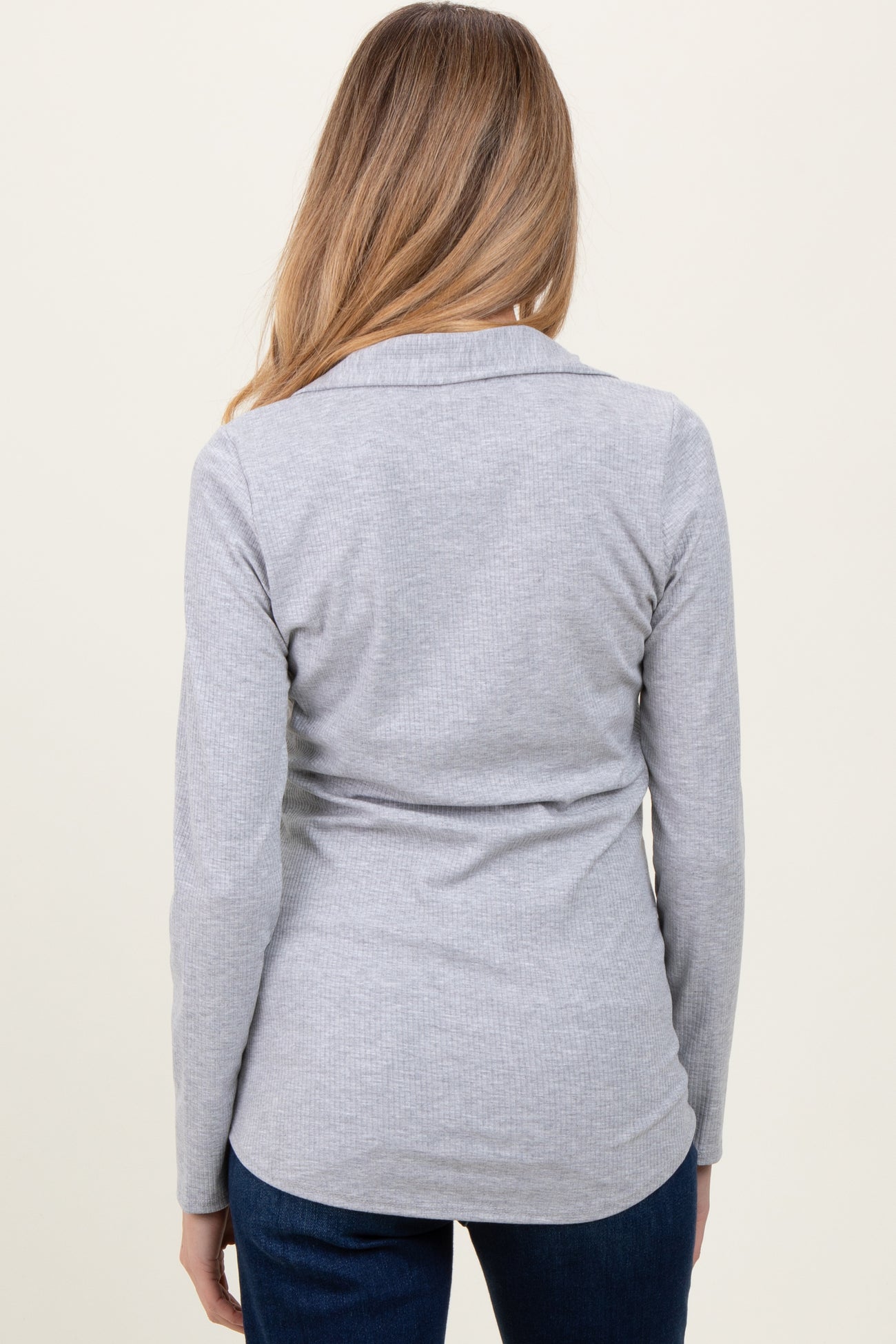 woman wearing a grey long sleeve maternity top, shown from the back, with a fitted style