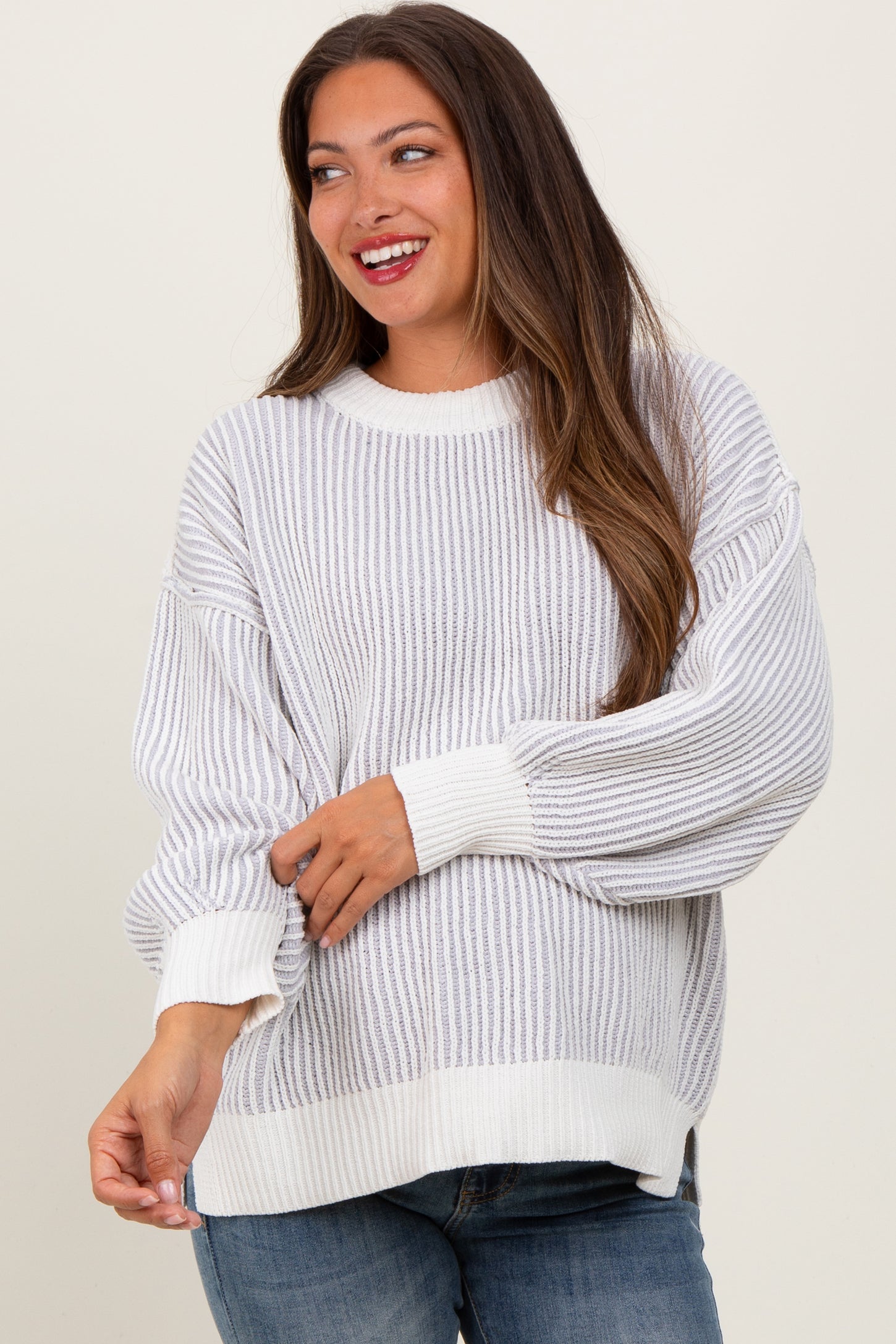 woman wearing a striped white and gray maternity sweater with balloon sleeves and a baby bump visible