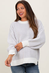 woman wearing a striped white and gray maternity sweater with balloon sleeves and a baby bump visible