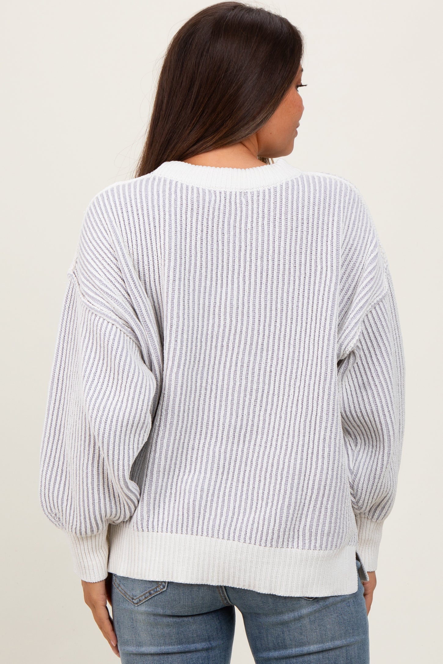 woman wearing a light gray and white striped maternity sweater with balloon sleeves, viewed from the back