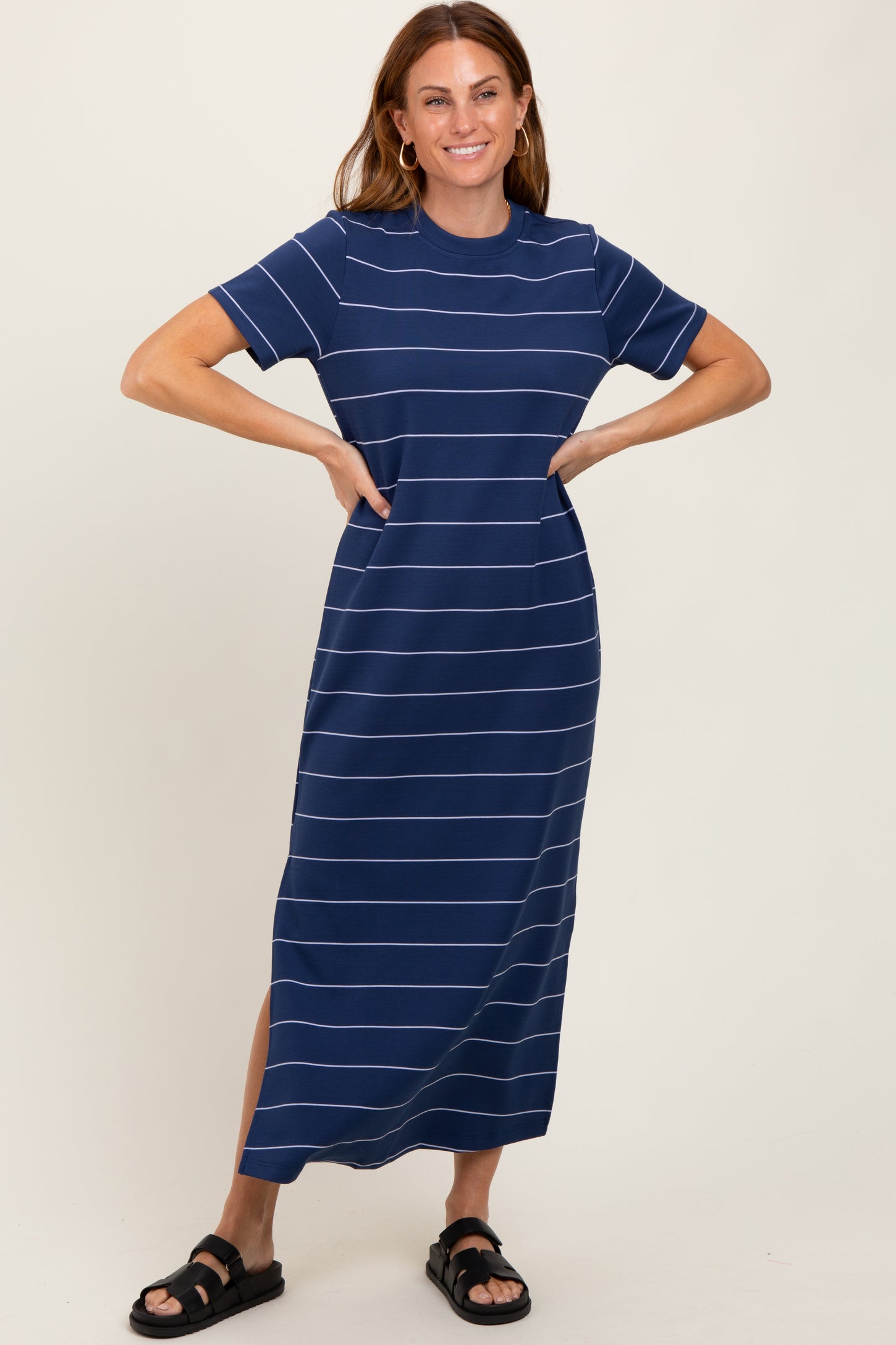 woman wearing a navy blue striped maxi dress with short sleeves and side slits, smiling while standing