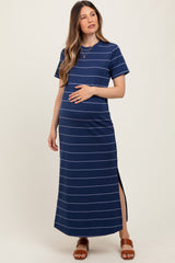 woman wearing a navy striped maternity maxi dress with a side slit and holding her baby bump