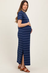 woman wearing a navy striped maternity maxi dress with a side slit and holding her baby bump