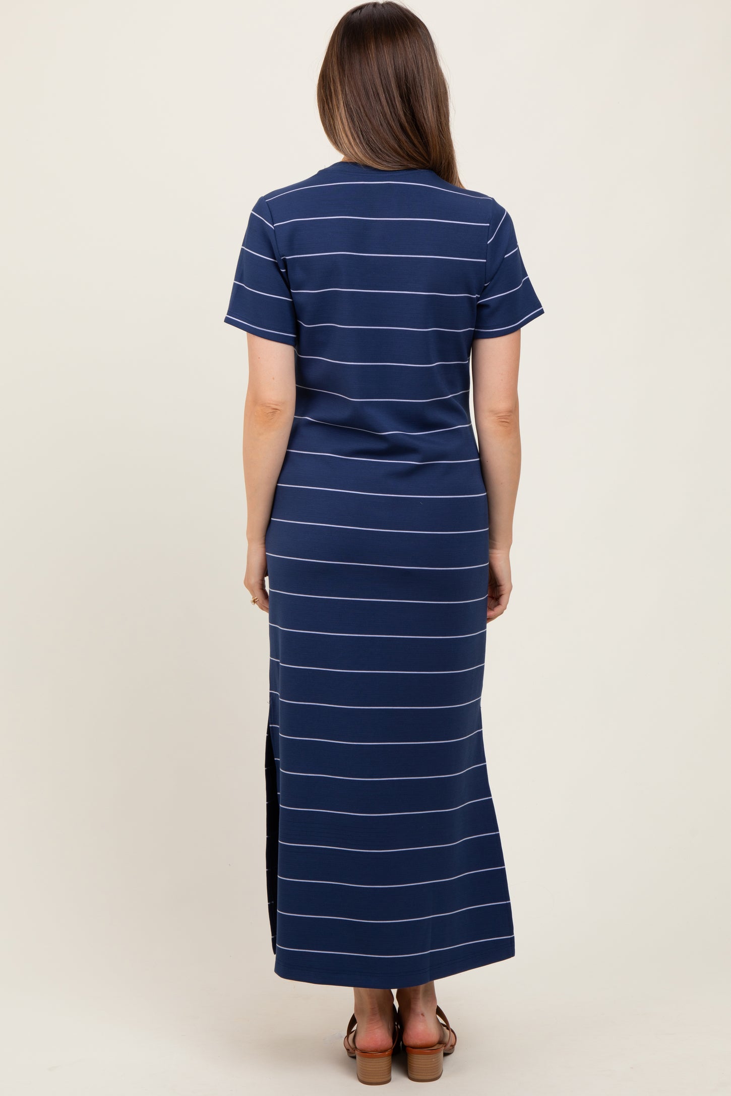 woman wearing a navy striped maternity maxi dress with short sleeves and side slits, showing a baby bump