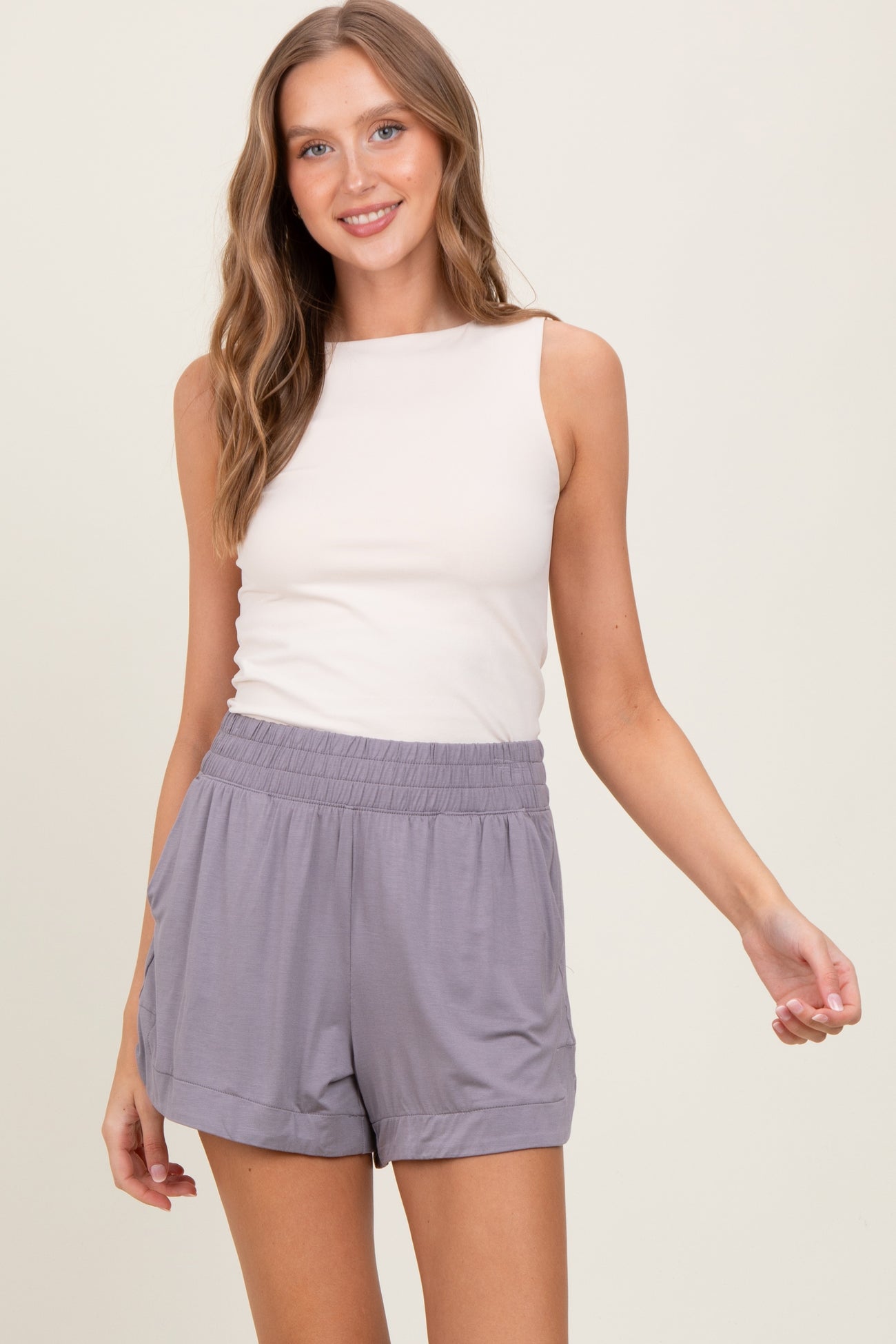 woman wearing a beige sleeveless top and gray relaxed-fit shorts with an elastic waistband