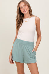 woman wearing a white sleeveless top and mint green casual shorts with side pockets