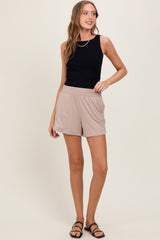 woman wearing a black sleeveless top and beige shorts with side pockets and a relaxed fit