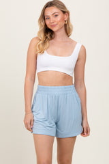woman wearing a white crop top and light blue elastic waist shorts