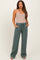 woman wearing a beige ribbed maternity bodysuit and green maternity sweatpants with pockets and a drawstring waist