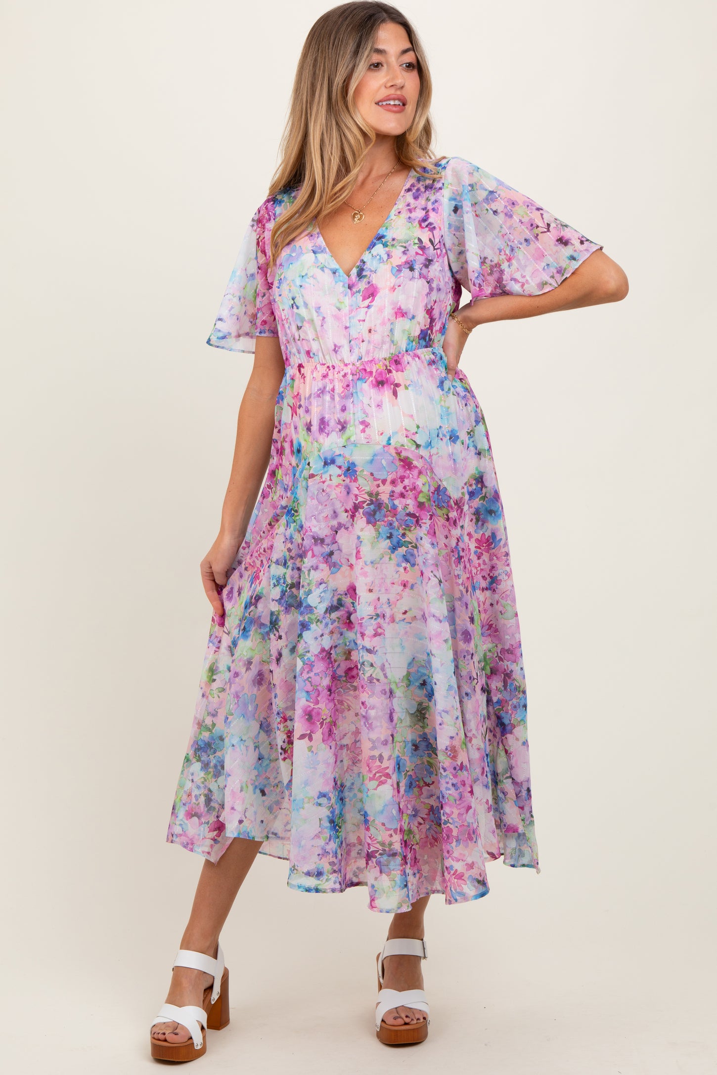 woman wearing a floral print maternity dress with short flutter sleeves and a v-neckline