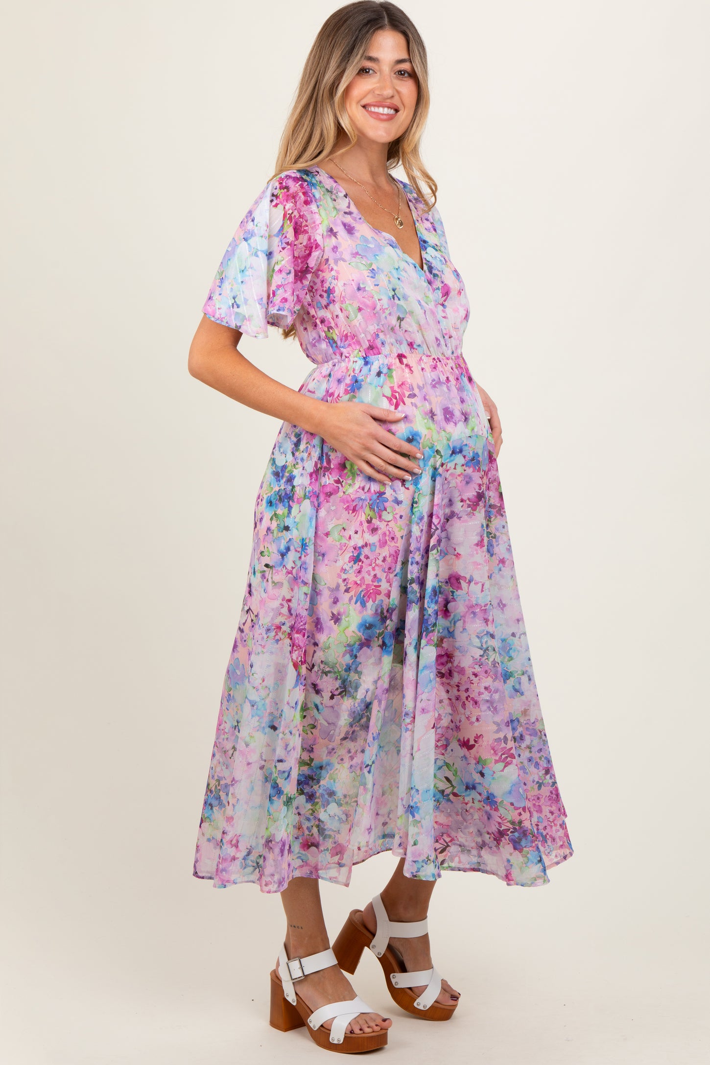 woman wearing a floral maternity dress with flutter sleeves and a baby bump visible