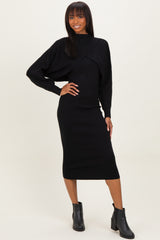 woman wearing a black long sleeve knitted midi dress with oversized sleeves and side draping