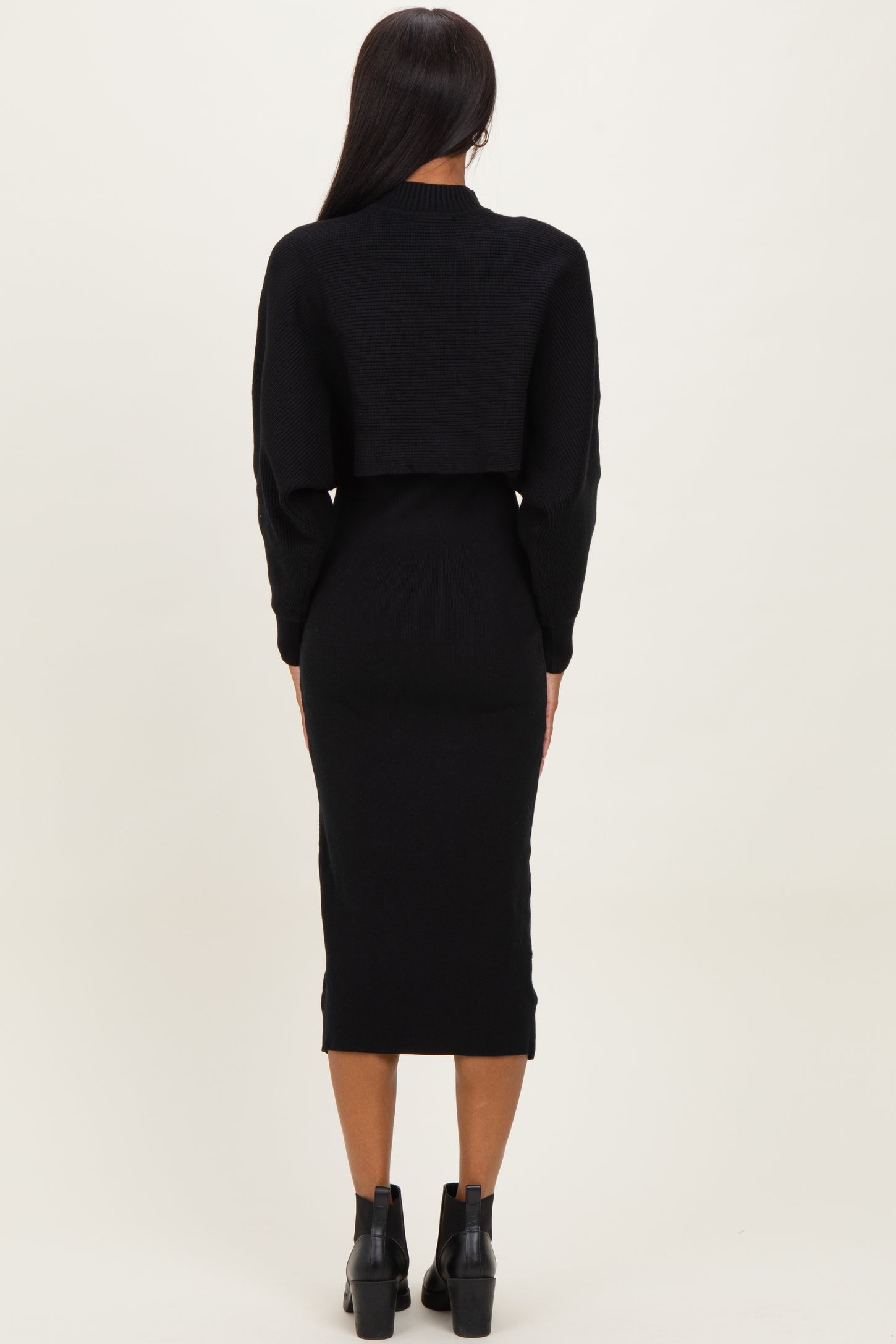 woman wearing a black cropped sweater and black midi dress, viewed from the back