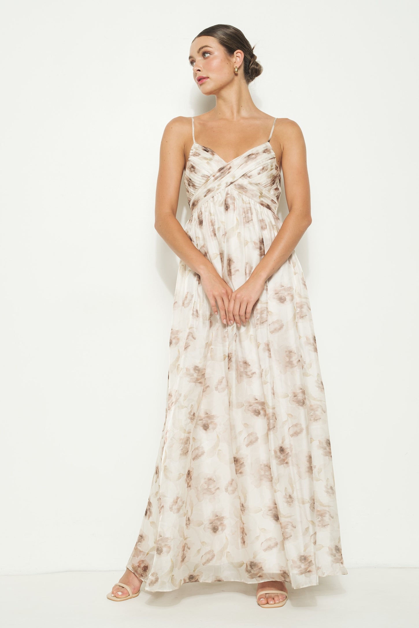 woman wearing a flowing floral maxi dress with spaghetti straps and a draped bust design